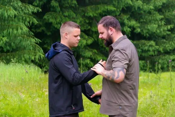 Zwei Personen stehen in einer Wiese und führen eine Übung durch