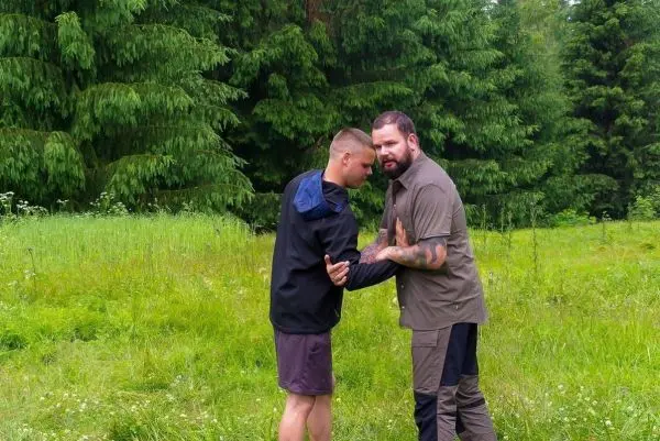 Zwei Personen üben eine Selbstverteidigungstechnik in einer grünen Wiese
