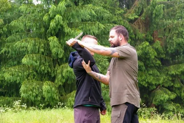 Zwei Personen üben eine Selbstverteidigungstechnik mit einem Messer im Freien