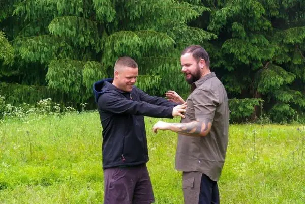 Zwei Personen üben eine Technik im Freien auf einer Wiese