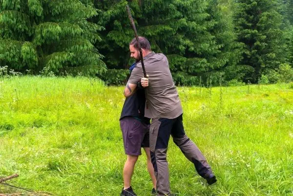 Zwei Personen üben eine Technik mit einem Stock in einer grünen Wiese