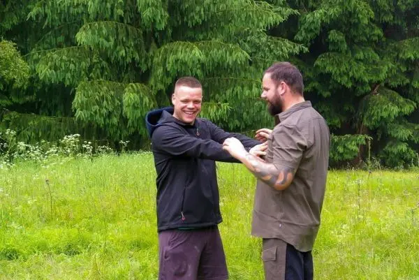 Zwei Personen üben eine Technik zur Befreiung aus einer Umklammerung im Freien