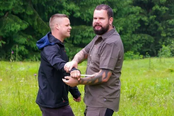 Zwei Personen üben eine Technik zur Handentwaffnung im Freien