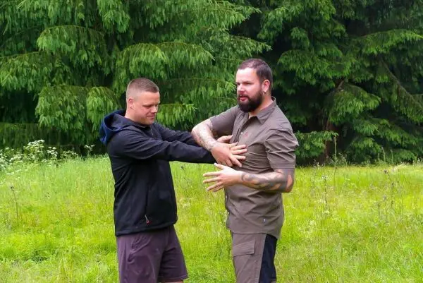Zwei Personen üben eine Technik zur Selbstverteidigung im Freien