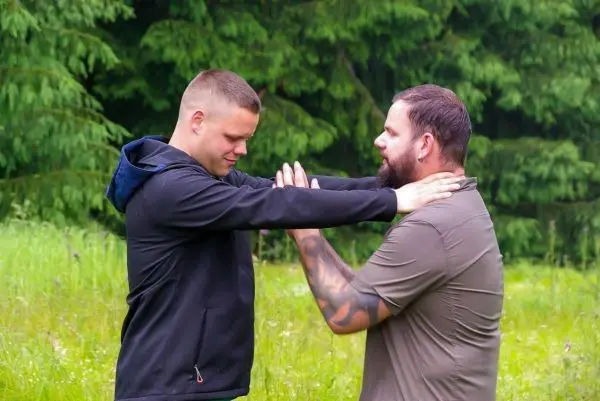 Zwei Personen üben eine Technik zur Selbstverteidigung im Freien