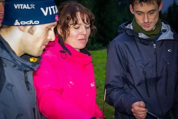 Drei Personen konzentrieren sich auf eine Kochstelle im Freien