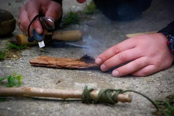 Feuerstahl erzeugt Funken auf Zunder, Rauch steigt auf