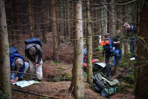 Gruppenmitglieder studieren Karten und bereiten Ausrüstung im Wald vor