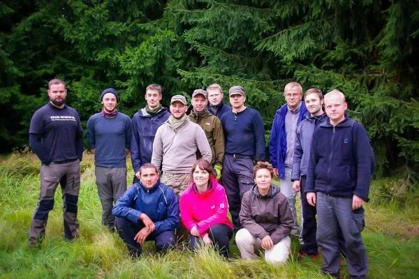 Gruppierung von Personen im Freien, umgeben von Bäumen und Gras