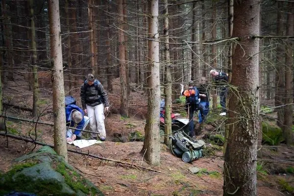 Gruppierung von Personen im Wald, einige studieren eine Karte, andere beobachten die Umgebung