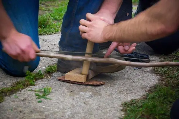 Holzstück mit Kerbe wird mit einem Stock bearbeitet