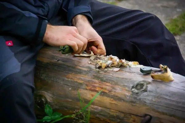 Holzstück wird mit einem Messer bearbeitet, Späne liegen daneben