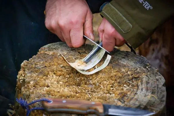 Holzstück wird mit einem Schnitzwerkzeug bearbeitet