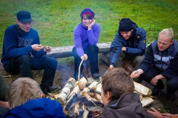 Kleines Bodenfeuer mit Holzscheiten, Gruppe sitzt im Kreis darum