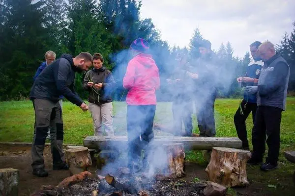 Kleines Bodenfeuer mit Rauch, mehrere Personen stehen um das Feuer