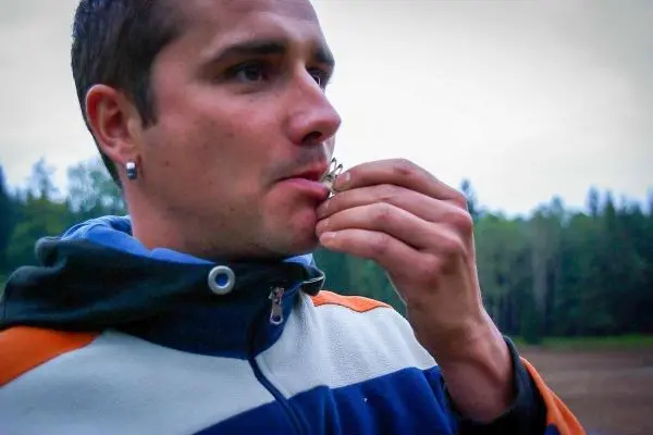 Mann bläst in ein Pfeifeninstrument und schaut konzentriert