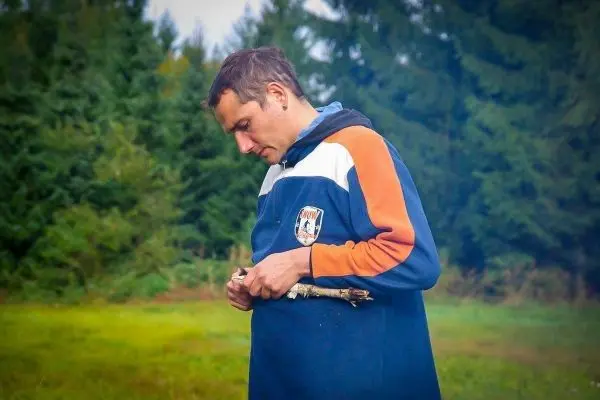 Mann hält einen Stock in der Hand und betrachtet ihn aufmerksam