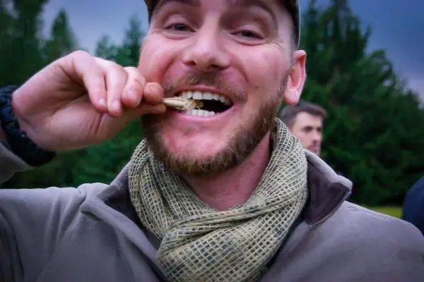 Mann hält essbare Insekten zwischen den Zähnen und lächelt