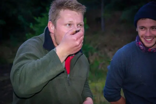 Mann hält etwas in der Hand und schaut konzentriert, ein anderer Mann lächelt