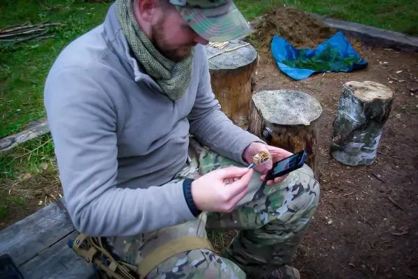 Mann hält Zunder in der Hand und schaut auf ein Smartphone