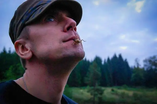 Mann mit einem kleinen Insekt im Mund schaut nach oben