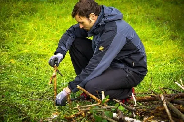 Messer schneidet Holzstück während das andere Ende auf dem Boden liegt