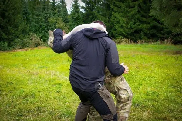 Person hebt andere Person an einem grünen Ort hoch