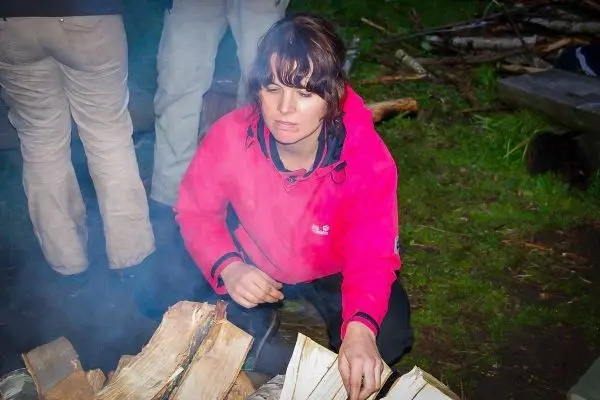 Zunder glimmt zwischen Holzscheiten, Rauch steigt auf
