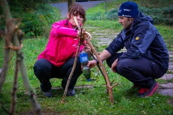 Zwei Personen bauen eine selbstgebaute Konstruktion aus Ästen und Schnur