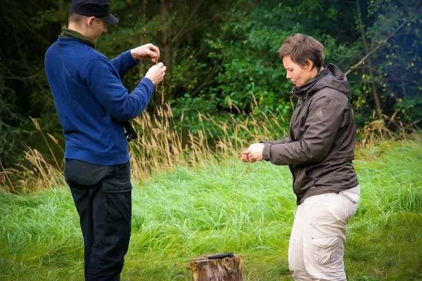 Zwei Personen binden Schnüre an einem Baumstumpf im Freien