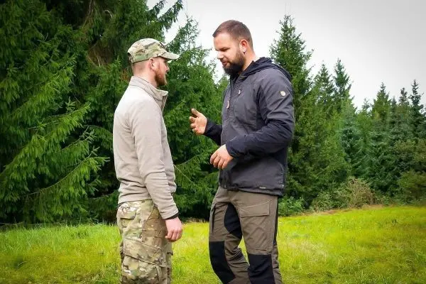 Zwei Personen stehen im Gespräch auf einer Wiese