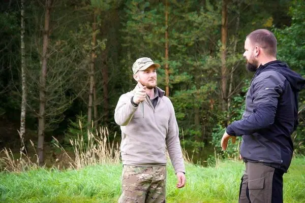 Zwei Personen stehen in einer grünen Wiese und unterhalten sich