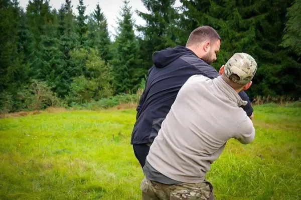 Zwei Personen üben eine Selbstverteidigungstechnik auf einer Wiese
