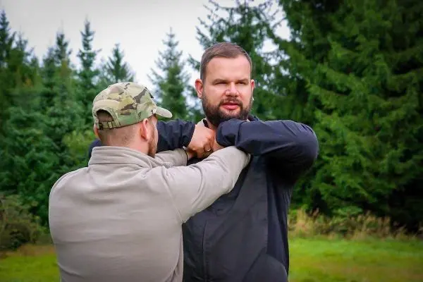 Zwei Personen üben eine Selbstverteidigungstechnik im Freien