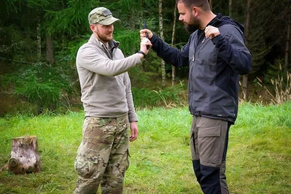 Zwei Personen üben eine Technik zur Handentwaffnung im Freien