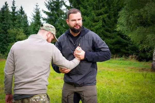 Zwei Personen üben eine Technik zur Kontrolle des Arms in einer Wiese