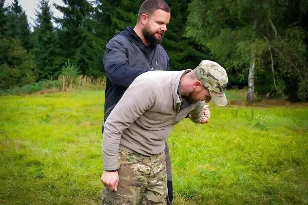 Zwei Personen üben eine Technik zur Kontrolle in einem grasbewachsenen Bereich