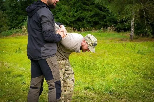 Zwei Personen üben eine Technik zur Kontrolle in einem grünen Feld