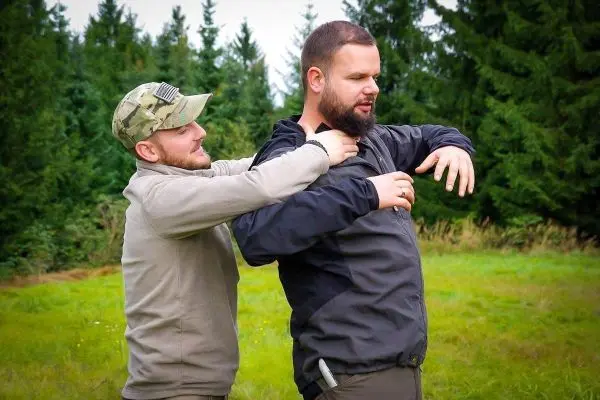 Zwei Personen üben eine Technik zur Selbstverteidigung im Freien