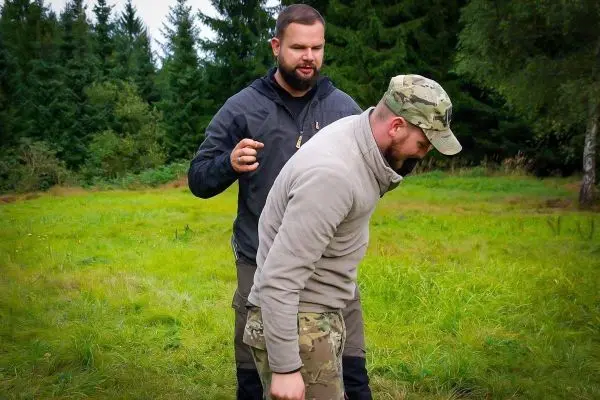 Zwei Personen üben eine Technik zur Unterstützung in einem grünen Feld