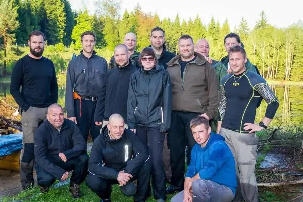 Gruppierung von Personen in Outdoor-Bekleidung am Ufer eines Gewässers