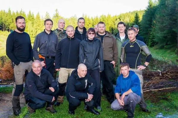 Gruppierung von Personen in Outdoor-Bekleidung vor bewaldeter Kulisse