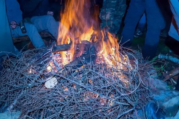 Kleine Flamme brennt auf einem Haufen aus Ästen und Holzstücken