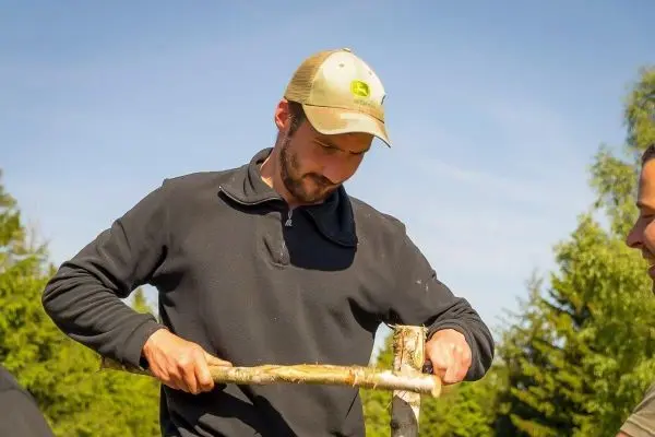 Mann bearbeitet einen Stock mit einem Messer zur Holzarbeit