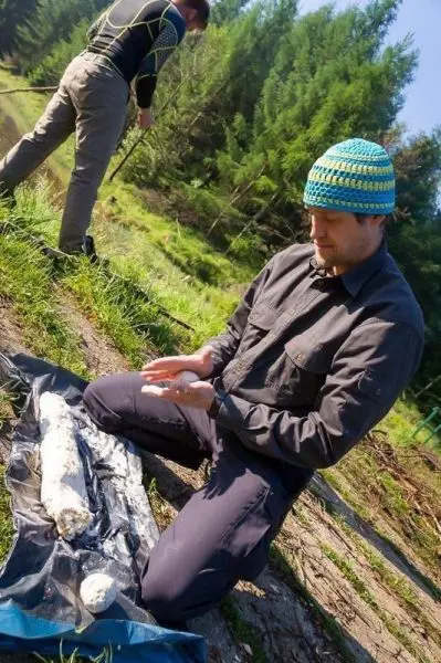 Mann knetet eine Mischung auf einer Plane im Wald