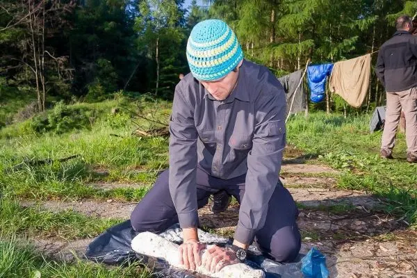 Mann knetet einen Teig auf einer blauen Plane im Wald