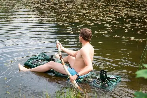 Mann paddelt auf improvisiertem Floß im Wasser