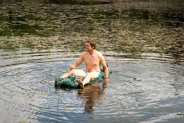 Mann sitzt auf einer improvisierten Schwimmhilfe im Wasser