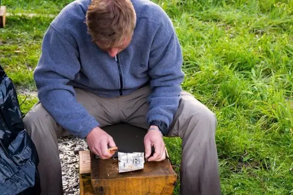 Messer bearbeitet Zunder auf einem Holzblock im Freien