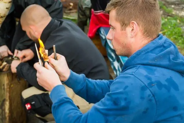 Person hält brennendes Material in der Hand beim Überlebenstraining